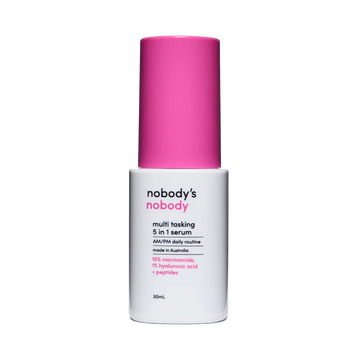 Nobody's Nobody multitasking 5 in 1 serum bottle with pink cap on black background